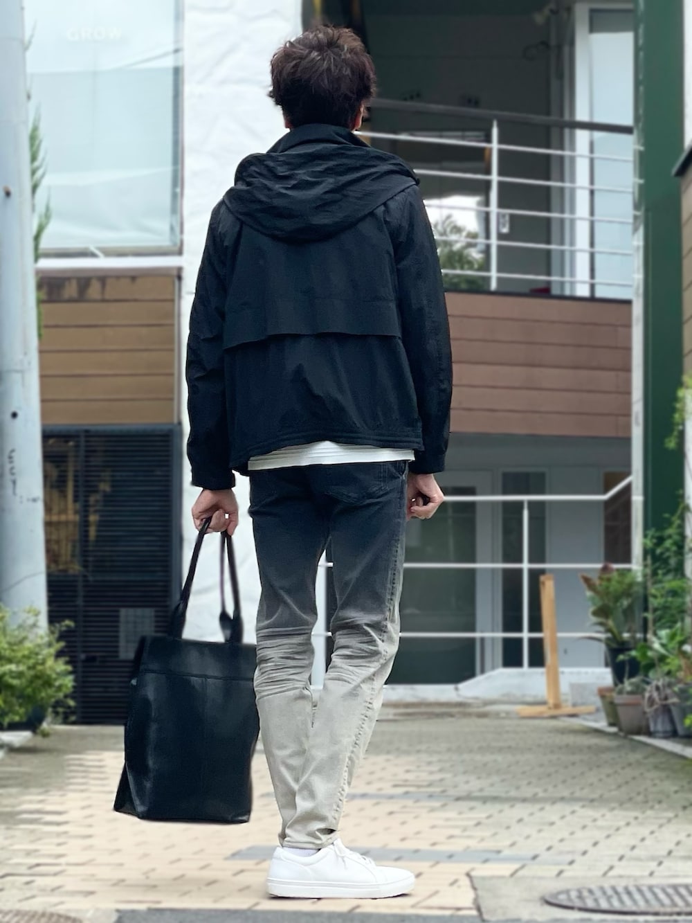 グレー系のブルゾン、ホワイト系のニット/セーター、ブラック系のデニムパンツを着用したメンズの秋コーディネートの3枚目の写真