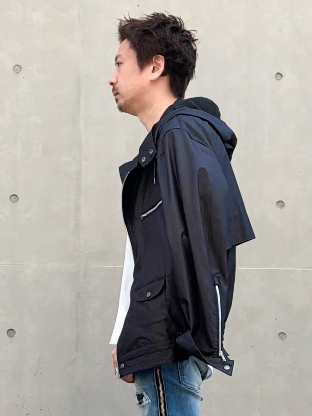 ブラック系のブルゾン、ホワイト系のシャツ/ブラウス、ブルー系のデニムパンツを着用したメンズの春コーディネートの2枚目の写真