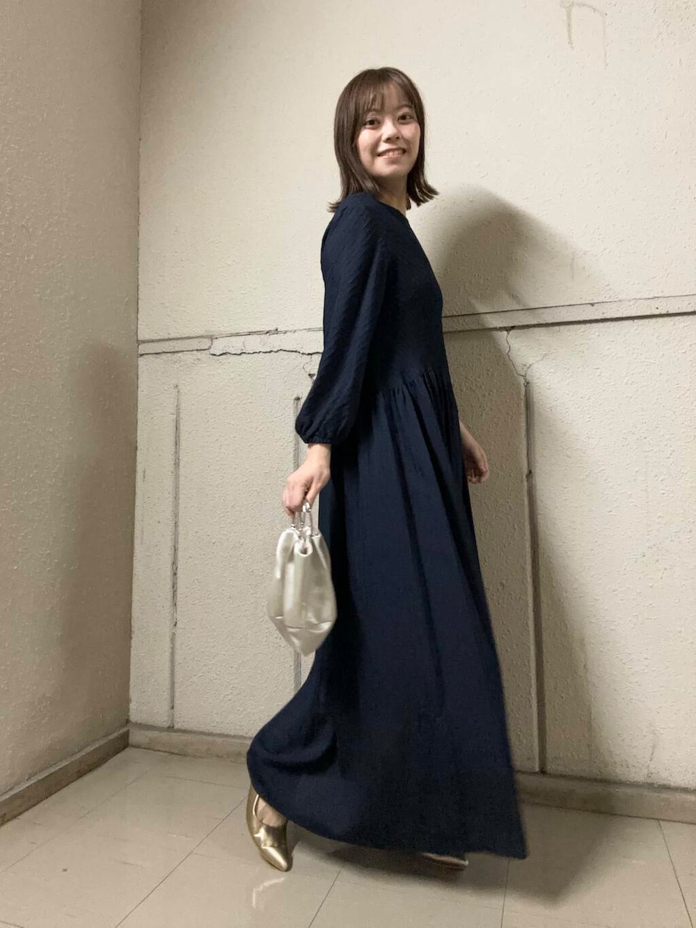 ゴールド系のパンプス、ベージュ系のハンドバッグ、ブルー系のワンピースを着用したレディースの夏コーディネートの2枚目の写真