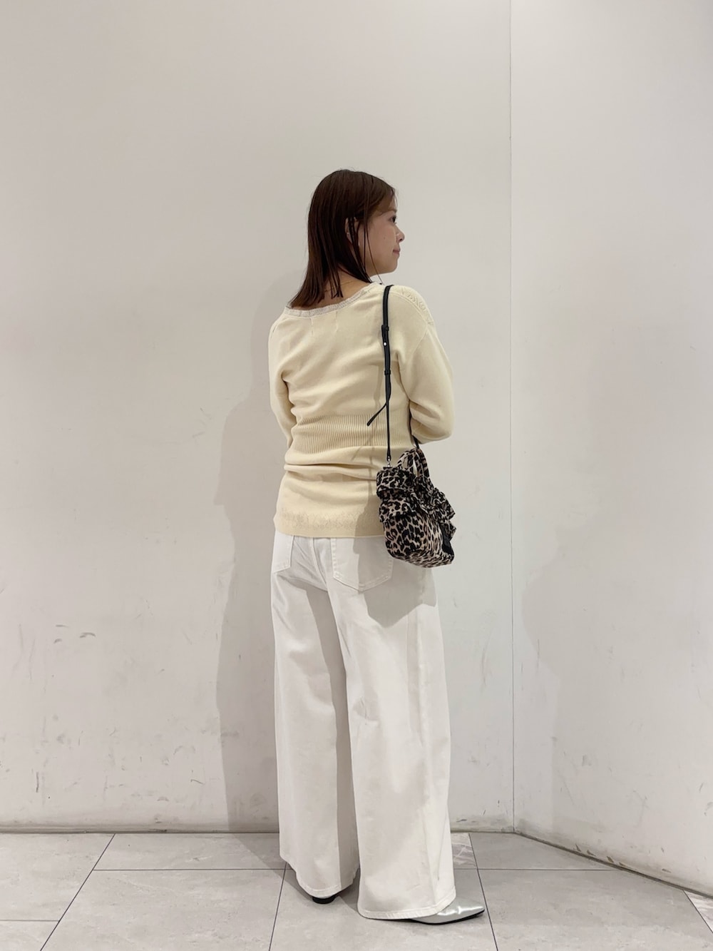 ホワイト系のニット/セーター、ホワイト系のデニムパンツ、シルバー系のパンプスを着用したレディースの春コーディネートの2枚目の写真