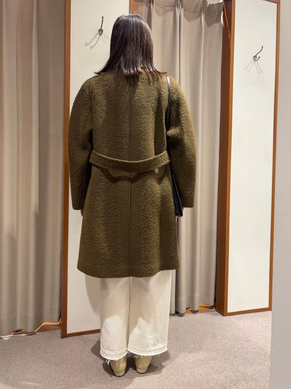 ホワイト系のデニムパンツ、ホワイト系のブーツ、ブラウン系のステンカラーコートを着用したレディースの冬コーディネートの3枚目の写真