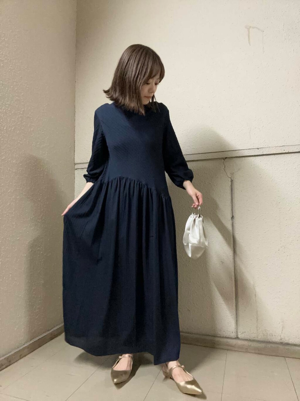 ゴールド系のパンプス、ベージュ系のハンドバッグ、ブルー系のワンピースを着用したレディースの夏コーディネートの3枚目の写真