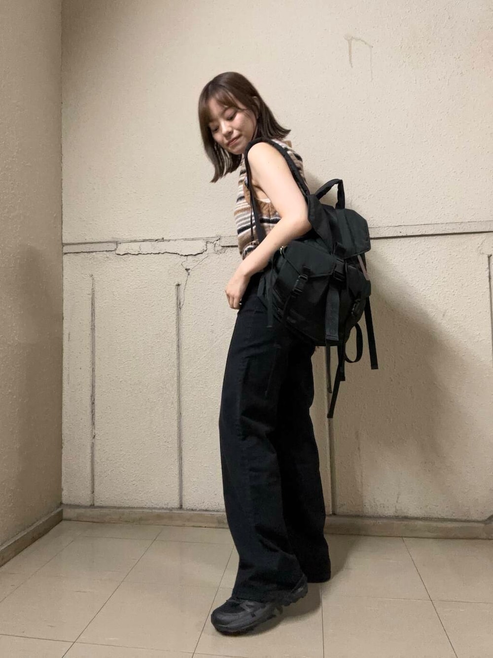 ブラウン系のベスト、ブラック系のバックパック/リュック、ブラック系のデニムパンツを着用したレディースの夏コーディネートの3枚目の写真