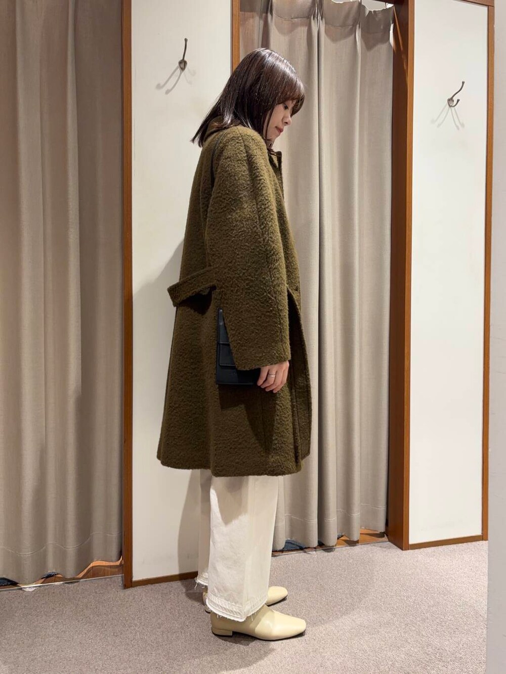 ホワイト系のデニムパンツ、ホワイト系のブーツ、ブラウン系のステンカラーコートを着用したレディースの冬コーディネートの2枚目の写真