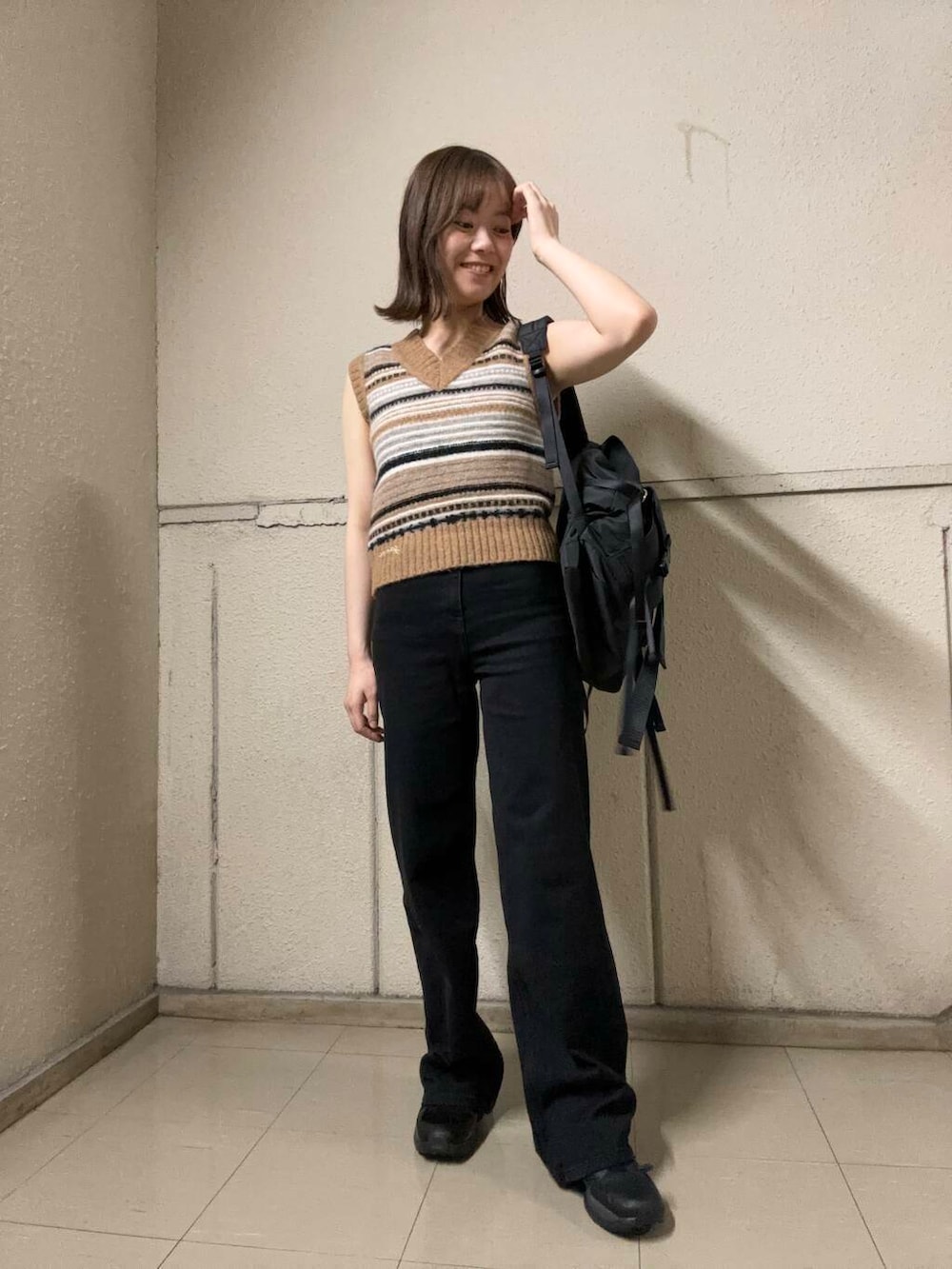 ブラウン系のベスト、ブラック系のバックパック/リュック、ブラック系のデニムパンツを着用したレディースの夏コーディネートの2枚目の写真