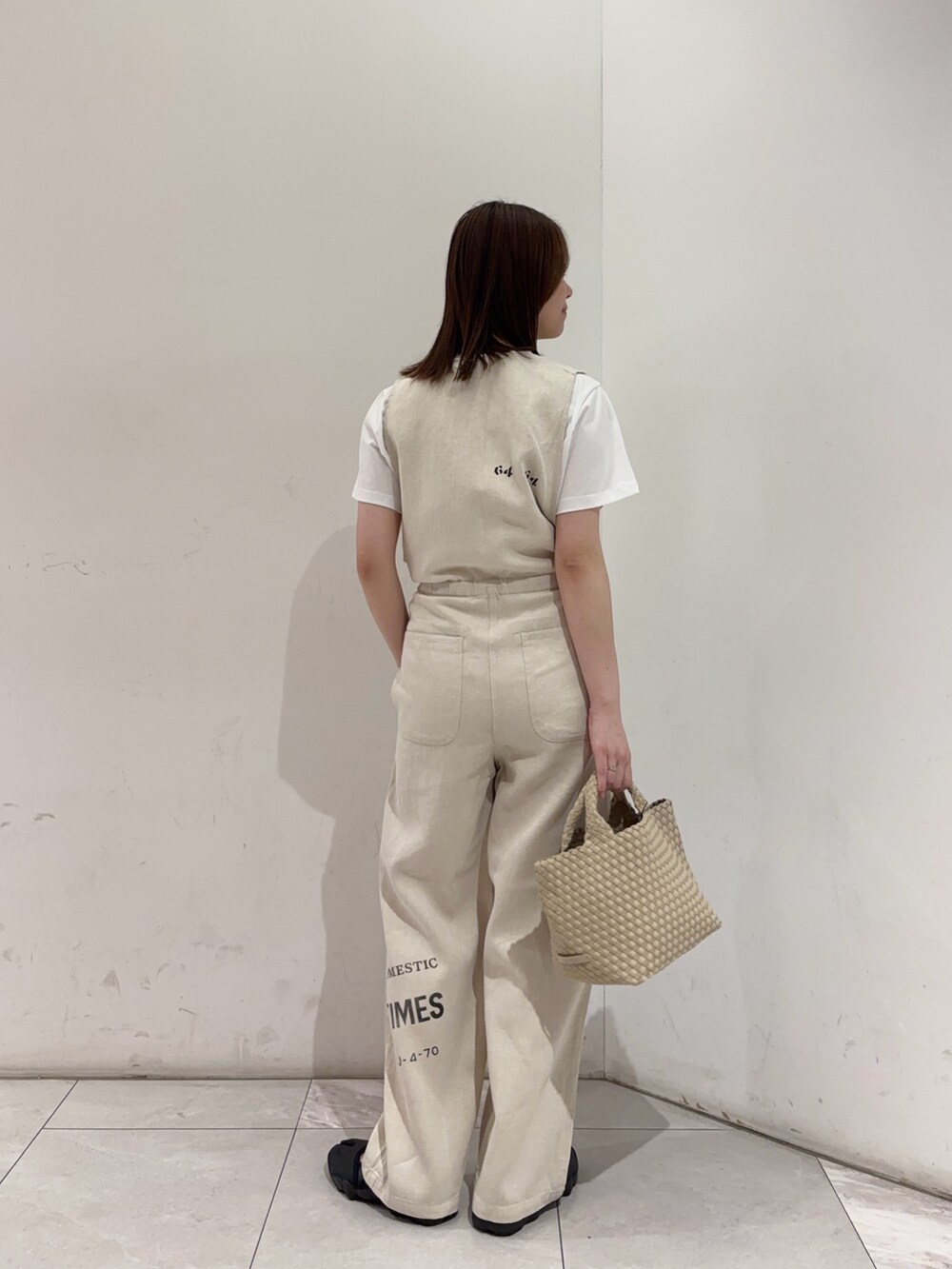 ベージュ系のその他パンツ、ホワイト系のトートバッグ、ブラック系のスニーカーを着用したレディースの春コーディネートの2枚目の写真