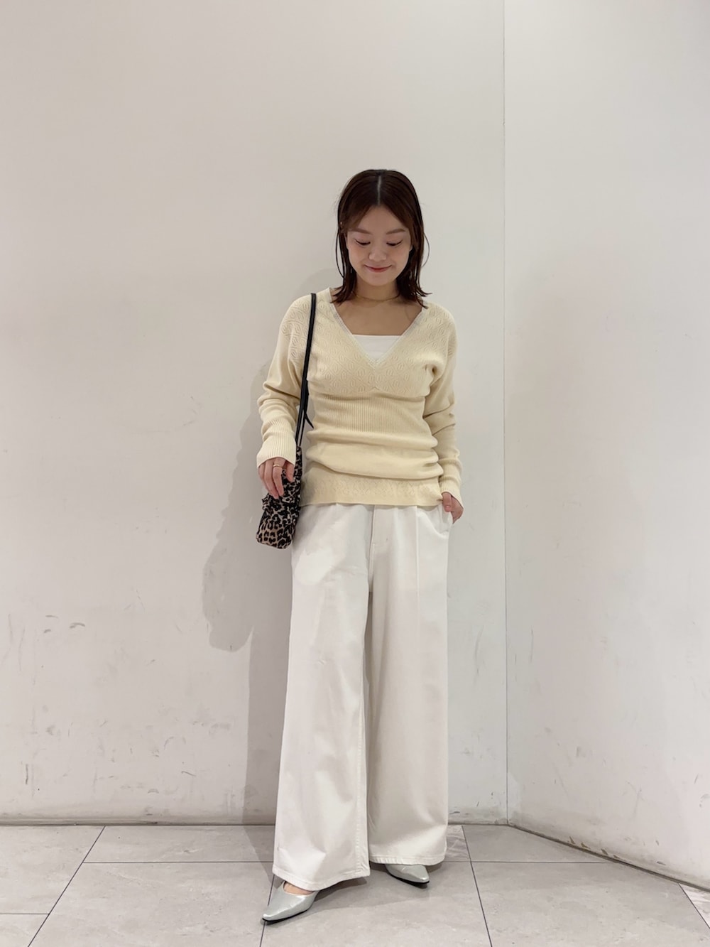 ホワイト系のニット/セーター、ホワイト系のデニムパンツ、シルバー系のパンプスを着用したレディースの春コーディネートの3枚目の写真