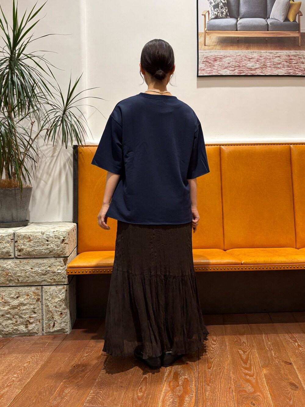 ブラウン系のスカート、ブルー系のTシャツ/カットソー、ゴールド系のネックレスを着用したレディースの秋コーディネートの2枚目の写真