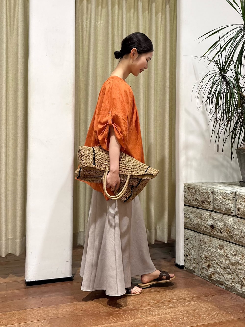 オレンジ系のシャツ/ブラウス、ベージュ系のトートバッグ、ベージュ系のスカートを着用したレディースの夏コーディネートの2枚目の写真