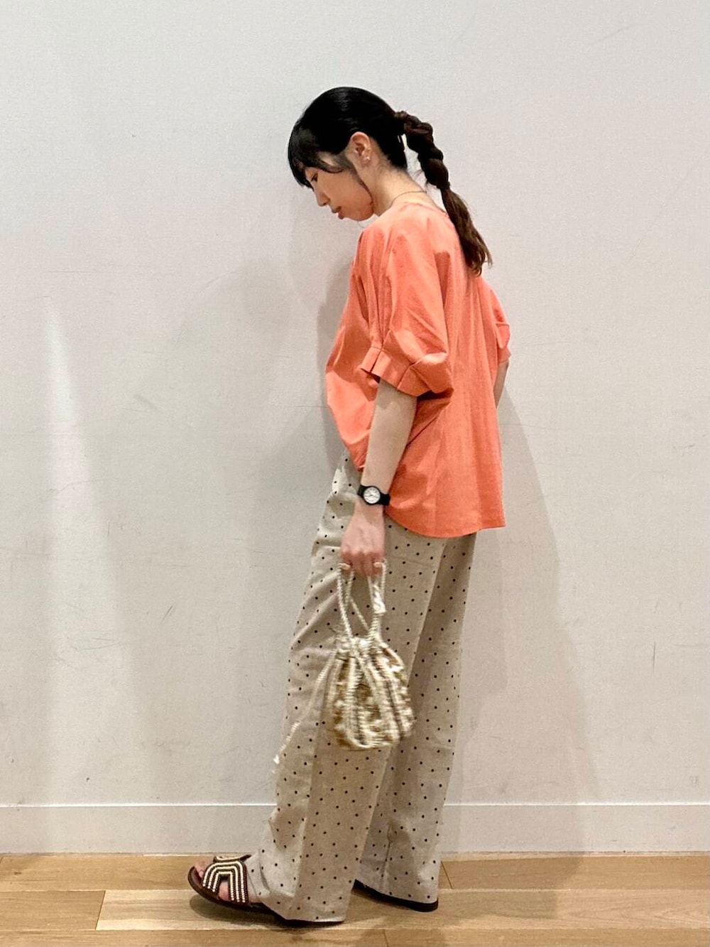 ベージュ系のその他パンツ、ブラウン系のサンダル、オレンジ系のTシャツ/カットソーを着用したレディースの夏コーディネートの4枚目の写真