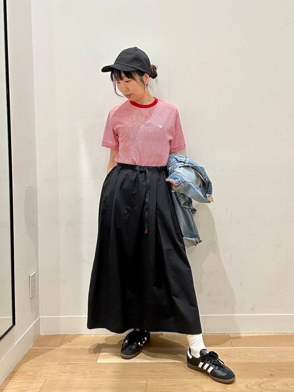 ブルー系のデニムジャケット、ホワイト系のバックパック/リュック、ブラック系のスカートを着用したレディースの春コーディネートの3枚目の写真