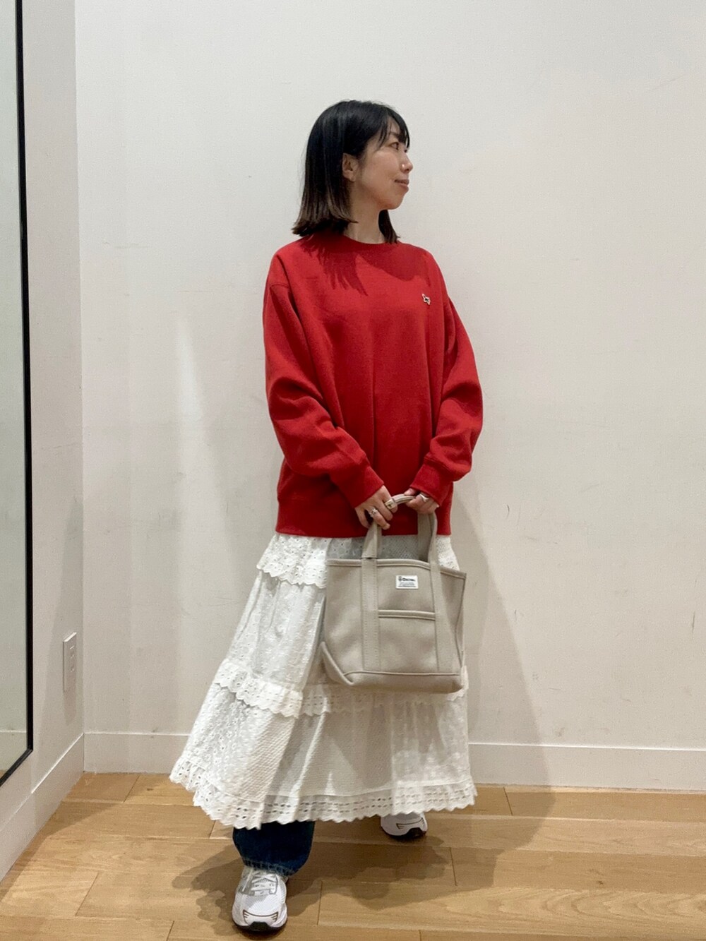 レッド系のスウェット、ブルー系のデニムパンツ、ホワイト系のスニーカーを着用したレディースの秋コーディネートの4枚目の写真