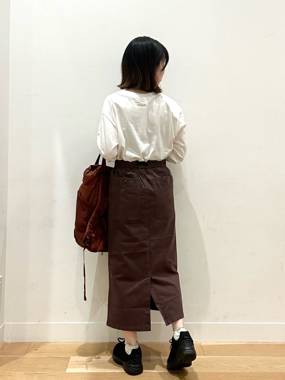 ブラウン系のスカート、グレー系のTシャツ/カットソー、ブラウン系のバックパック/リュックを着用したレディースの秋コーディネートの3枚目の写真