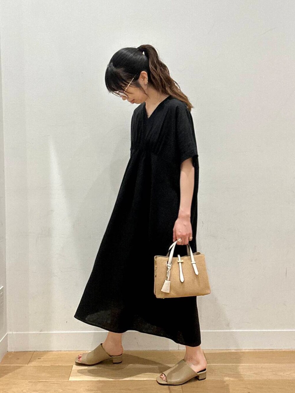 イエロー系のサンダル、ベージュ系のトートバッグ、ブラック系のワンピースを着用したレディースの夏コーディネートの4枚目の写真