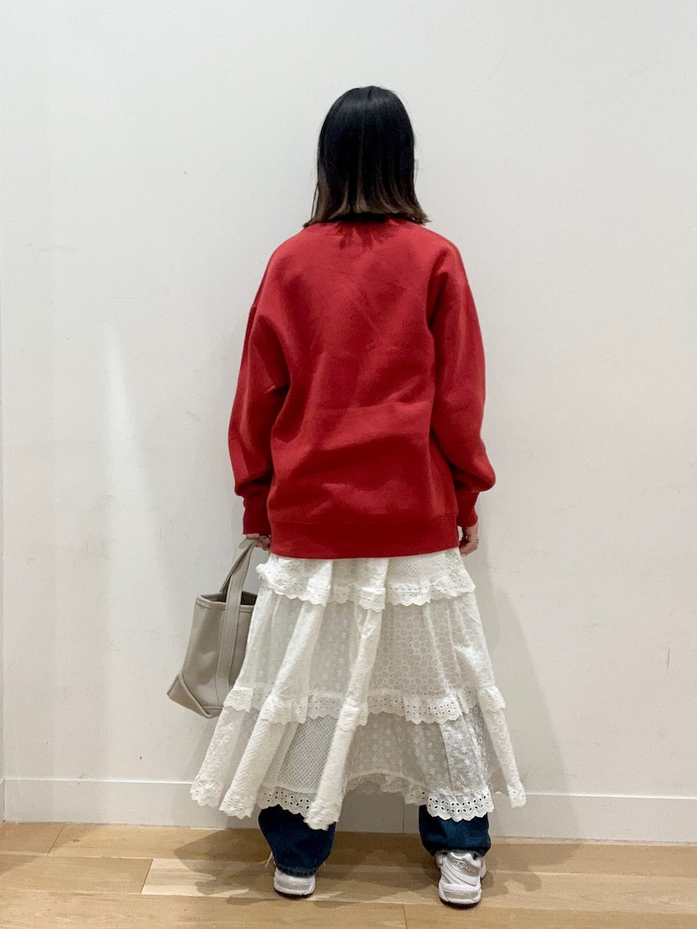 レッド系のスウェット、ブルー系のデニムパンツ、ホワイト系のスニーカーを着用したレディースの秋コーディネートの2枚目の写真