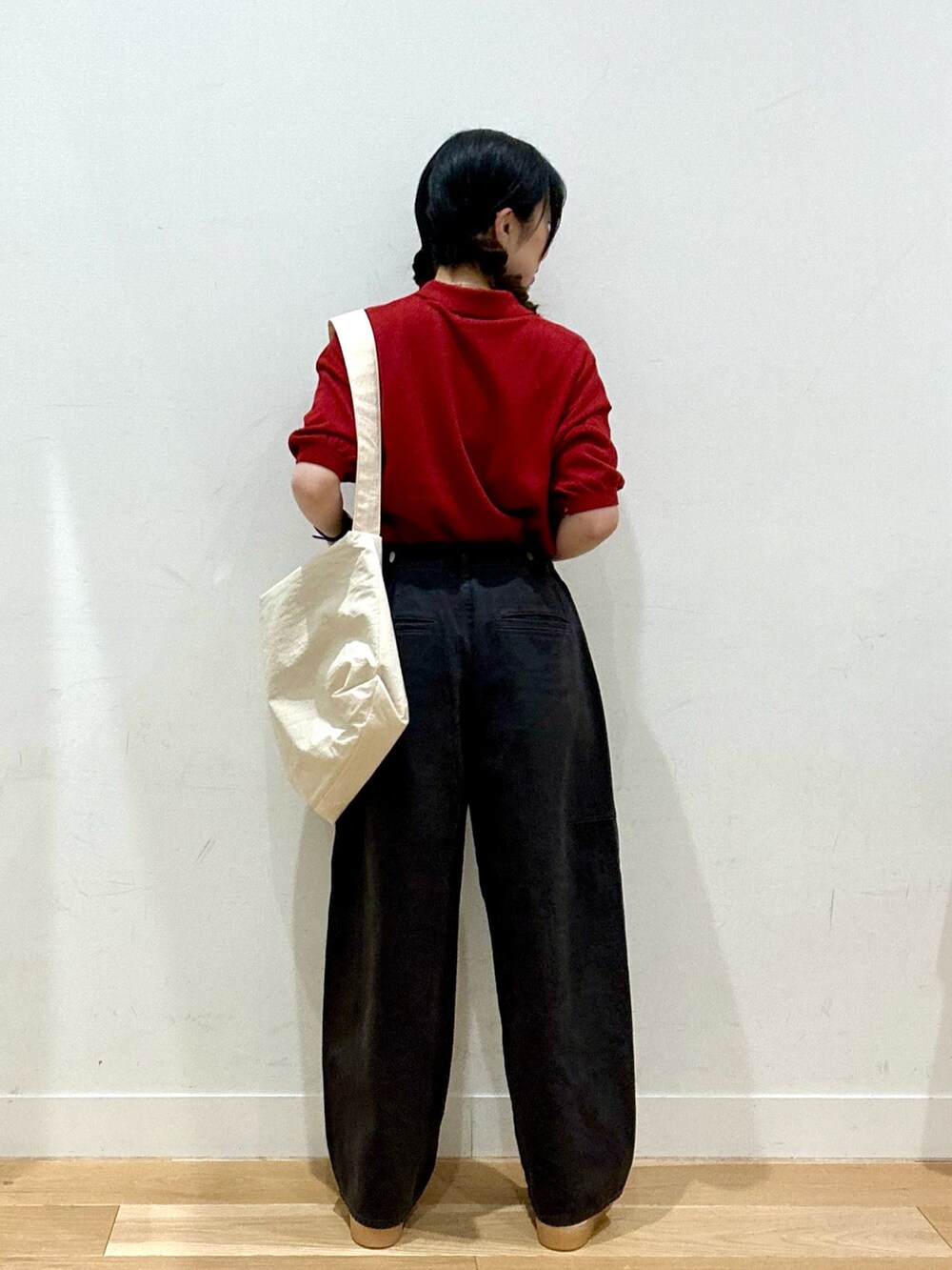 レッド系のニット/セーター、ホワイト系のショルダーバッグ、ブラック系のパンツを着用したレディースの夏コーディネートの3枚目の写真