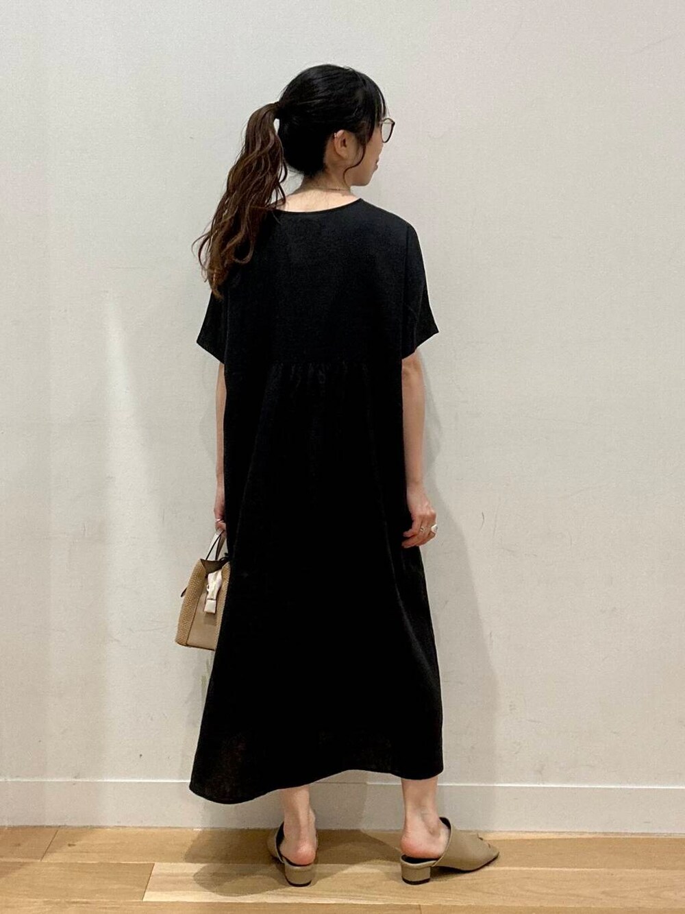 イエロー系のサンダル、ベージュ系のトートバッグ、ブラック系のワンピースを着用したレディースの夏コーディネートの3枚目の写真