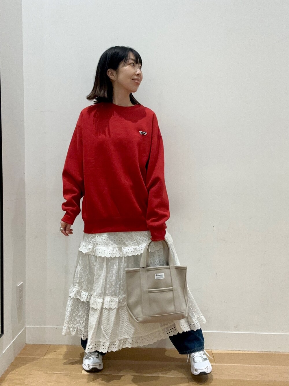 レッド系のスウェット、ブルー系のデニムパンツ、ホワイト系のスニーカーを着用したレディースの秋コーディネートの5枚目の写真