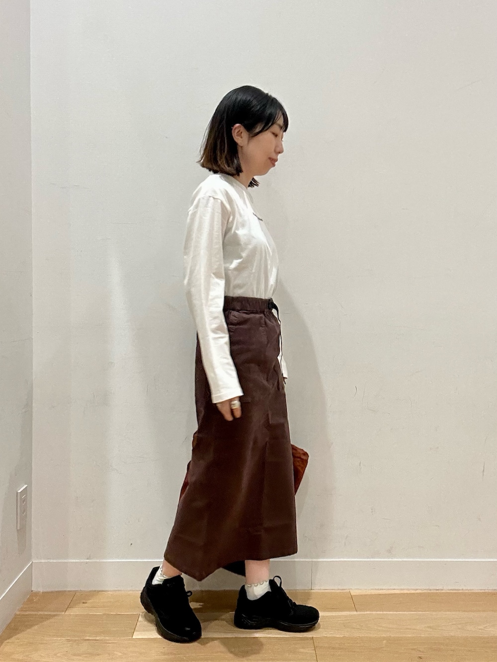 ブラウン系のスカート、グレー系のTシャツ/カットソー、ブラウン系のバックパック/リュックを着用したレディースの秋コーディネートの5枚目の写真