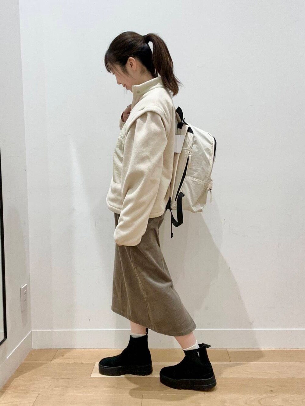 ホワイト系のバックパック/リュック、ブラウン系のスカート、ホワイト系のTシャツ/カットソーを着用したレディースの秋コーディネートの4枚目の写真