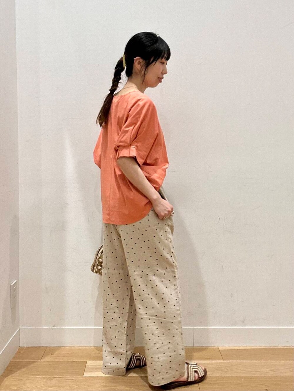 ベージュ系のその他パンツ、ブラウン系のサンダル、オレンジ系のTシャツ/カットソーを着用したレディースの夏コーディネートの2枚目の写真