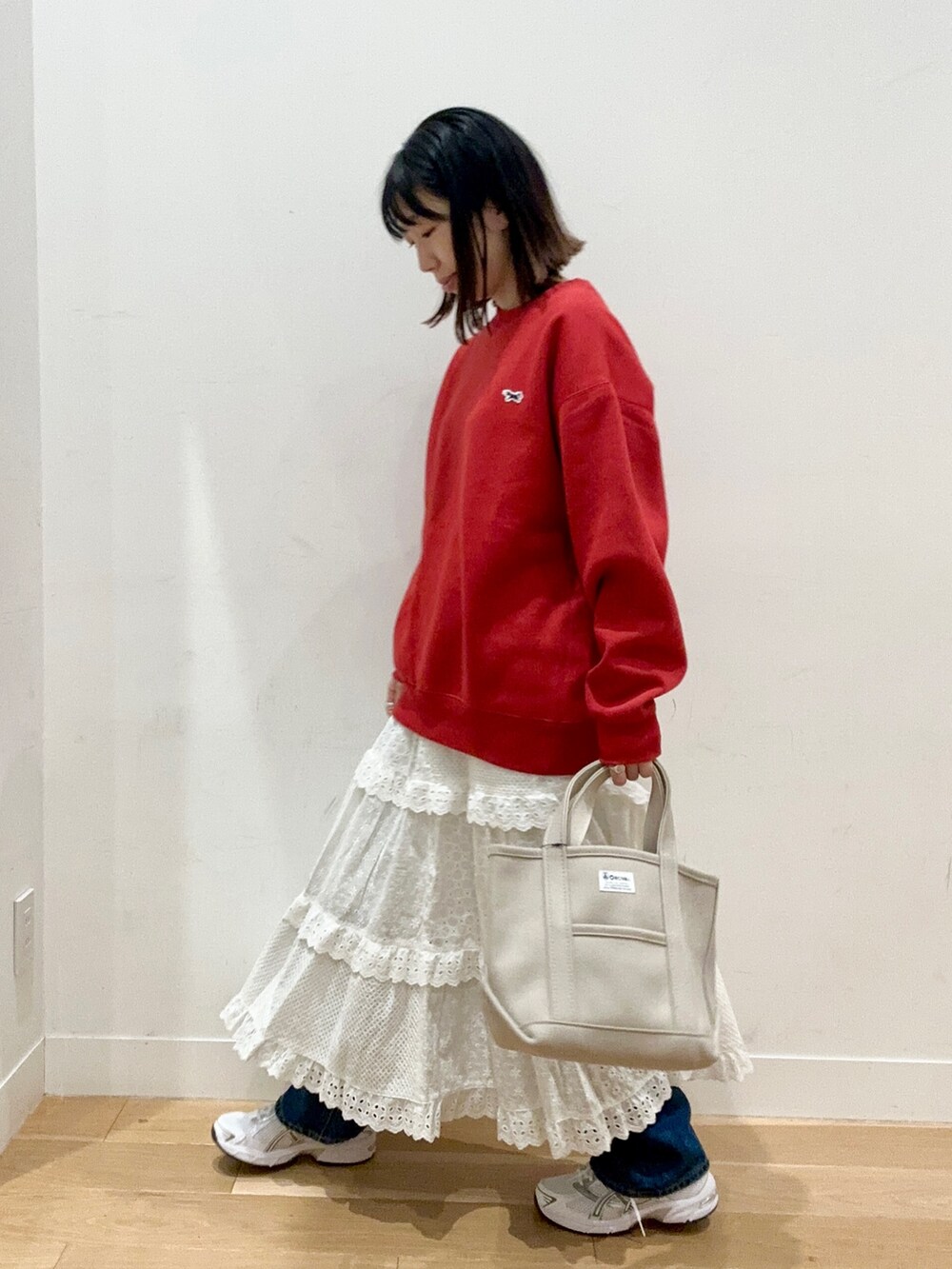 レッド系のスウェット、ブルー系のデニムパンツ、ホワイト系のスニーカーを着用したレディースの秋コーディネートの3枚目の写真