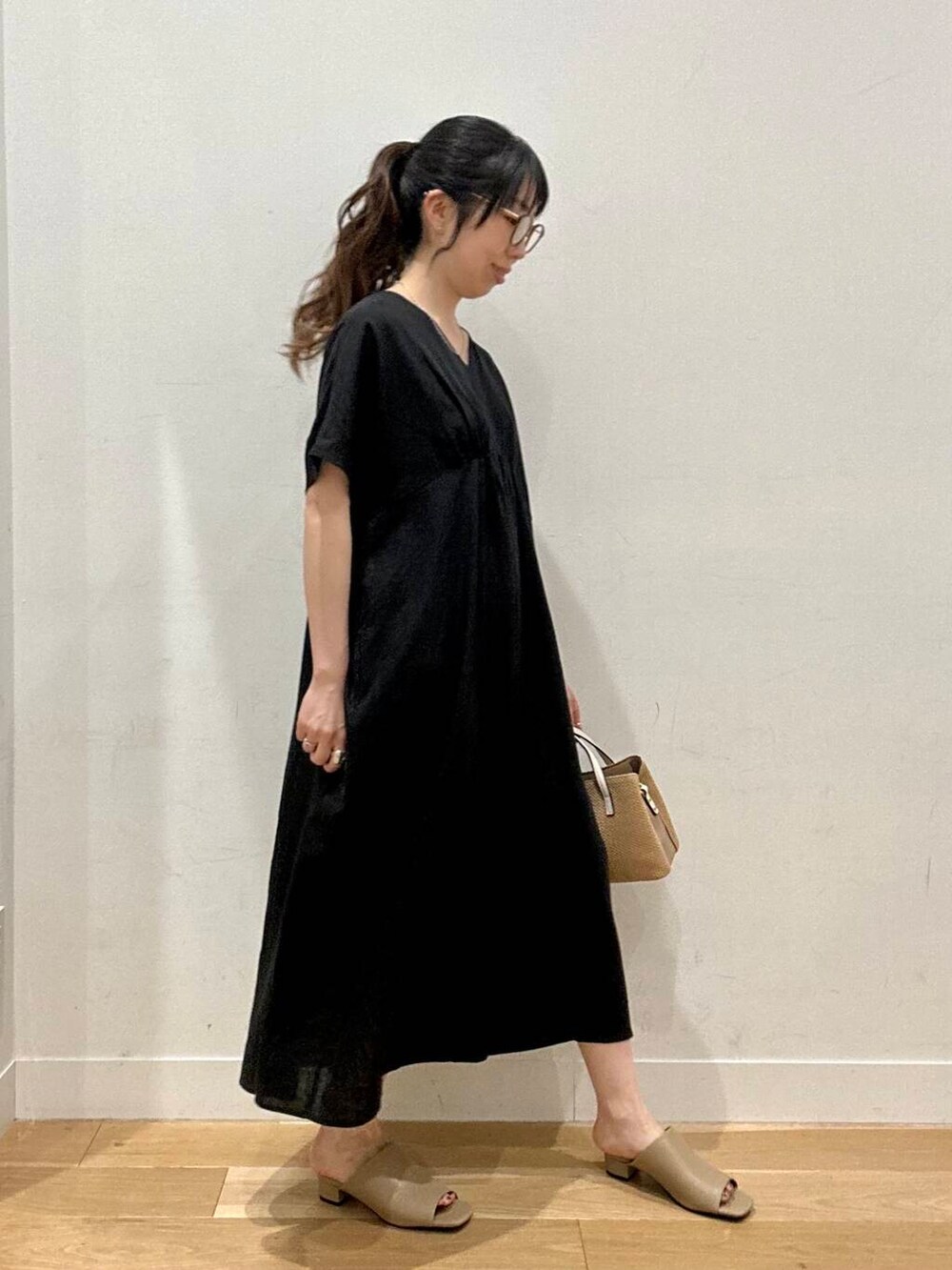 イエロー系のサンダル、ベージュ系のトートバッグ、ブラック系のワンピースを着用したレディースの夏コーディネートの2枚目の写真