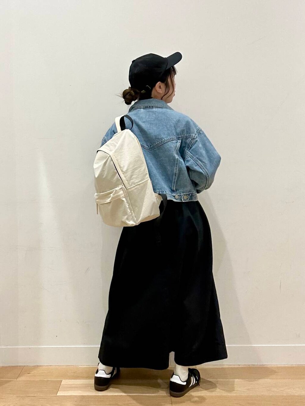 ブルー系のデニムジャケット、ホワイト系のバックパック/リュック、ブラック系のスカートを着用したレディースの春コーディネートの2枚目の写真
