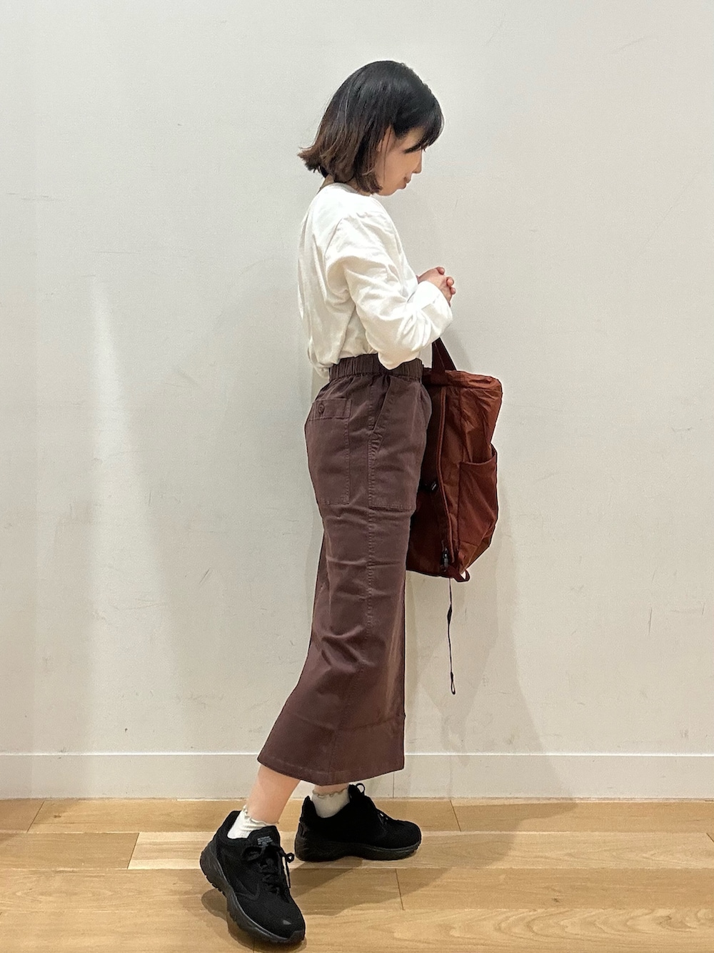 ブラウン系のスカート、グレー系のTシャツ/カットソー、ブラウン系のバックパック/リュックを着用したレディースの秋コーディネートの2枚目の写真