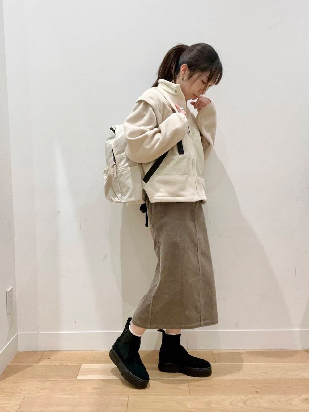 ホワイト系のバックパック/リュック、ブラウン系のスカート、ホワイト系のTシャツ/カットソーを着用したレディースの秋コーディネートの2枚目の写真