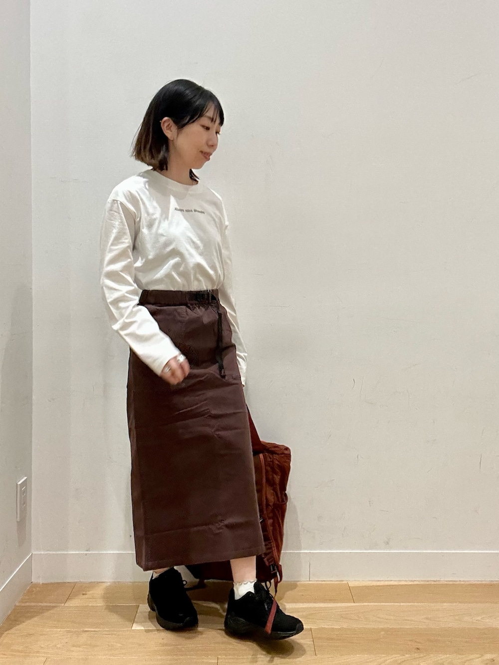 ブラウン系のスカート、グレー系のTシャツ/カットソー、ブラウン系のバックパック/リュックを着用したレディースの秋コーディネートの4枚目の写真