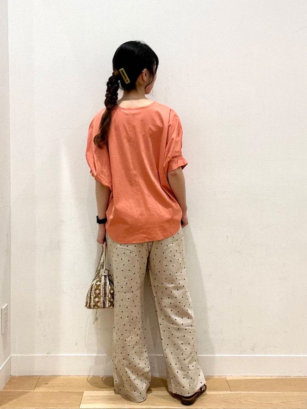 ベージュ系のその他パンツ、ブラウン系のサンダル、オレンジ系のTシャツ/カットソーを着用したレディースの夏コーディネートの3枚目の写真