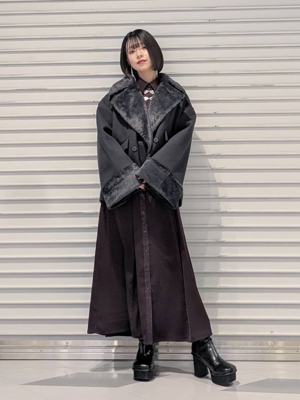 グレー系のチェスターコート、ブラック系のブーツ、レッド系のワンピースを着用したレディースの冬コーディネートの5枚目の写真