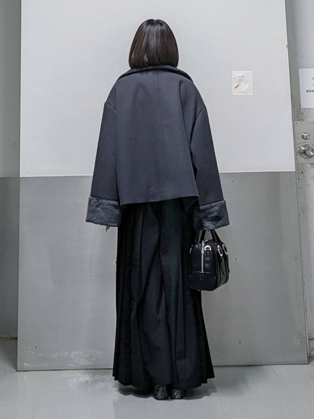 グレー系のチェスターコート、ブラック系のボストンバッグ、グレー系のブーツを着用したレディースの秋コーディネートの5枚目の写真