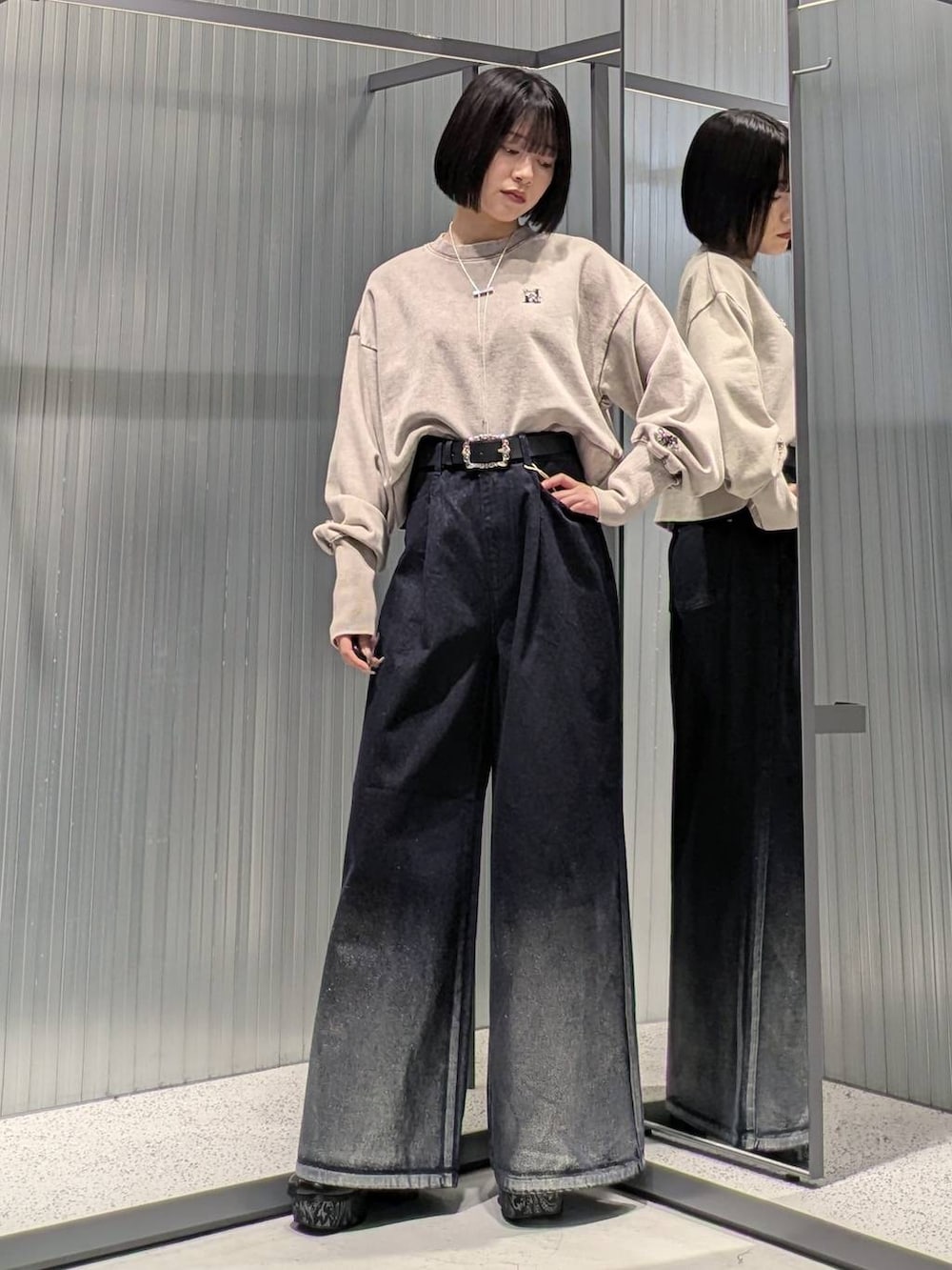 グレー系のブーツ、ブルー系のデニムパンツ、ベージュ系のスウェットを着用したレディースの秋コーディネートの2枚目の写真