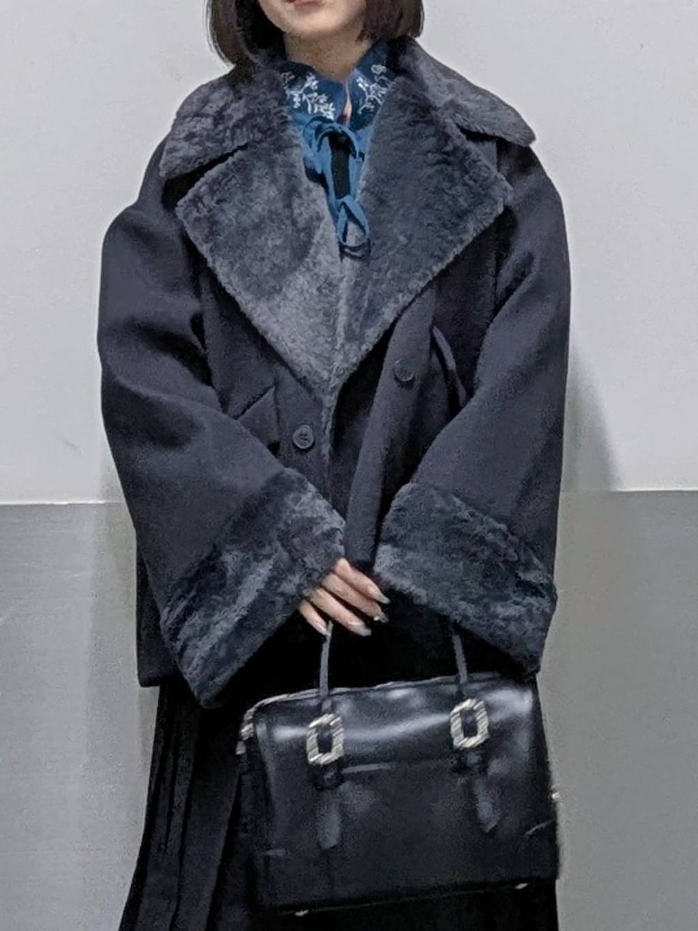 グレー系のチェスターコート、ブラック系のボストンバッグ、グレー系のブーツを着用したレディースの秋コーディネートの2枚目の写真