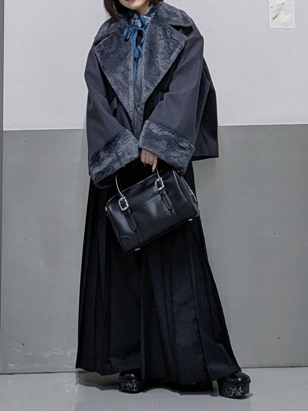 グレー系のチェスターコート、ブラック系のボストンバッグ、グレー系のブーツを着用したレディースの秋コーディネートの6枚目の写真