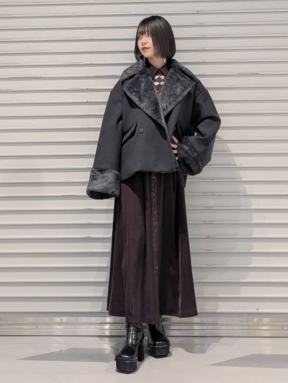 グレー系のチェスターコート、ブラック系のブーツ、レッド系のワンピースを着用したレディースの冬コーディネートの4枚目の写真