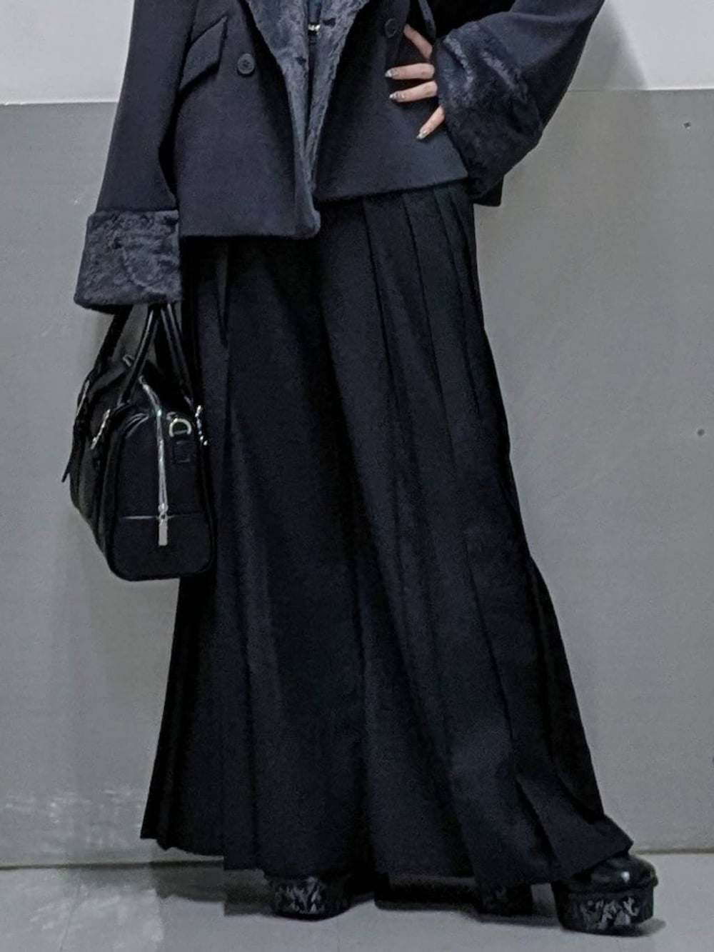 グレー系のチェスターコート、ブラック系のボストンバッグ、グレー系のブーツを着用したレディースの秋コーディネートの3枚目の写真