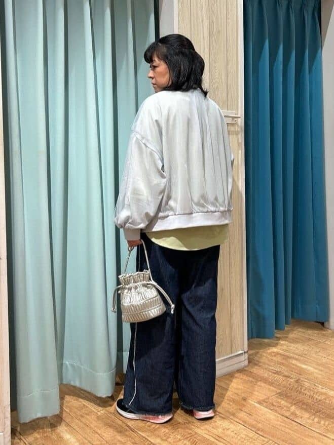 グレー系のブルゾン、グリーン系のシャツ/ブラウス、ブルー系のデニムパンツを着用したレディースの春コーディネートの3枚目の写真