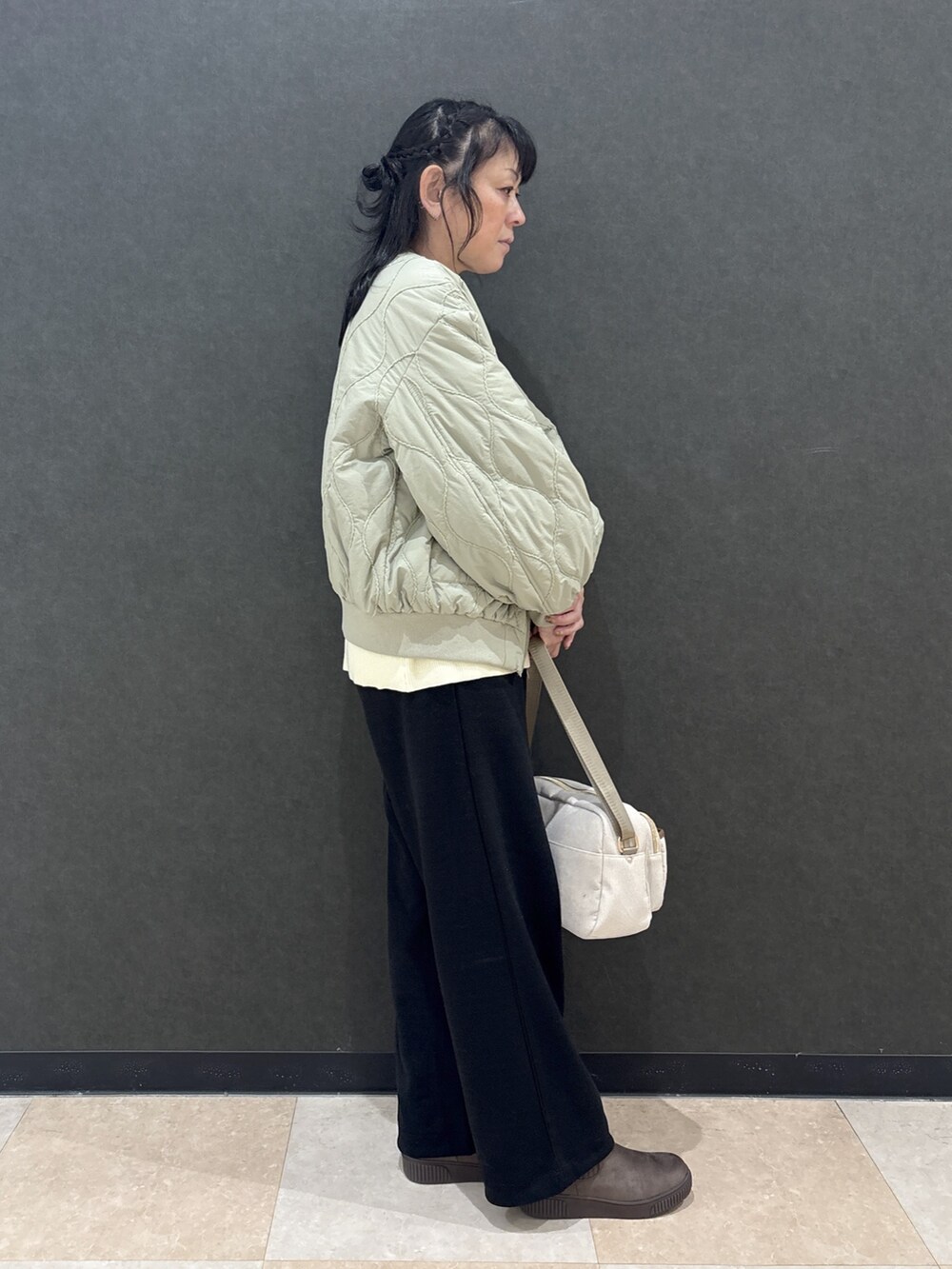 グリーン系のブルゾン、ホワイト系のニット/セーター、ブラック系のその他パンツを着用したレディースの秋コーディネートの2枚目の写真