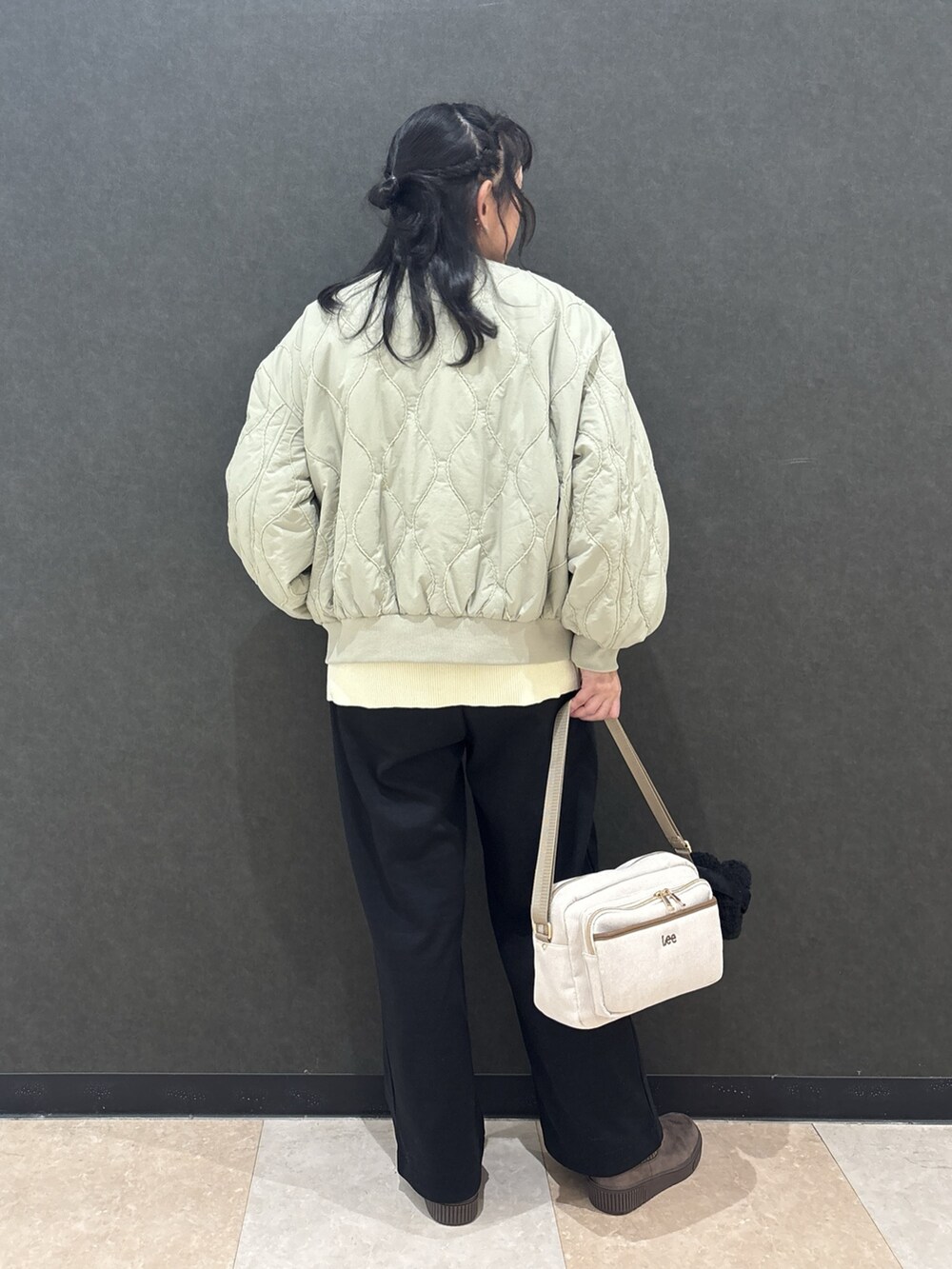 グリーン系のブルゾン、ホワイト系のニット/セーター、ブラック系のその他パンツを着用したレディースの秋コーディネートの3枚目の写真