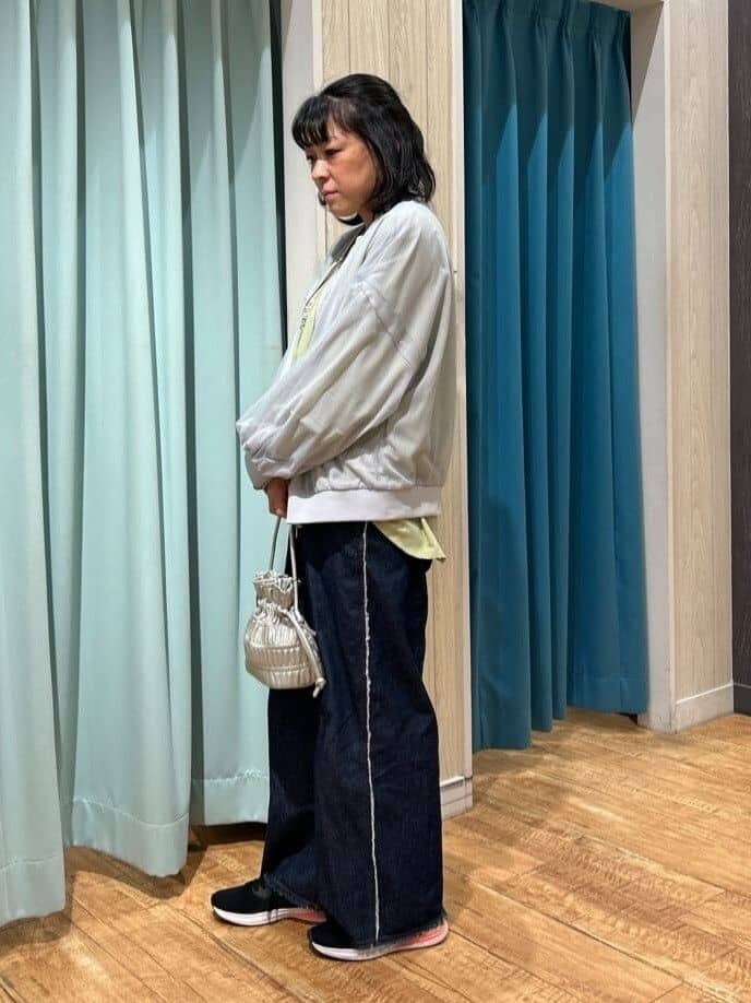 グレー系のブルゾン、グリーン系のシャツ/ブラウス、ブルー系のデニムパンツを着用したレディースの春コーディネートの2枚目の写真