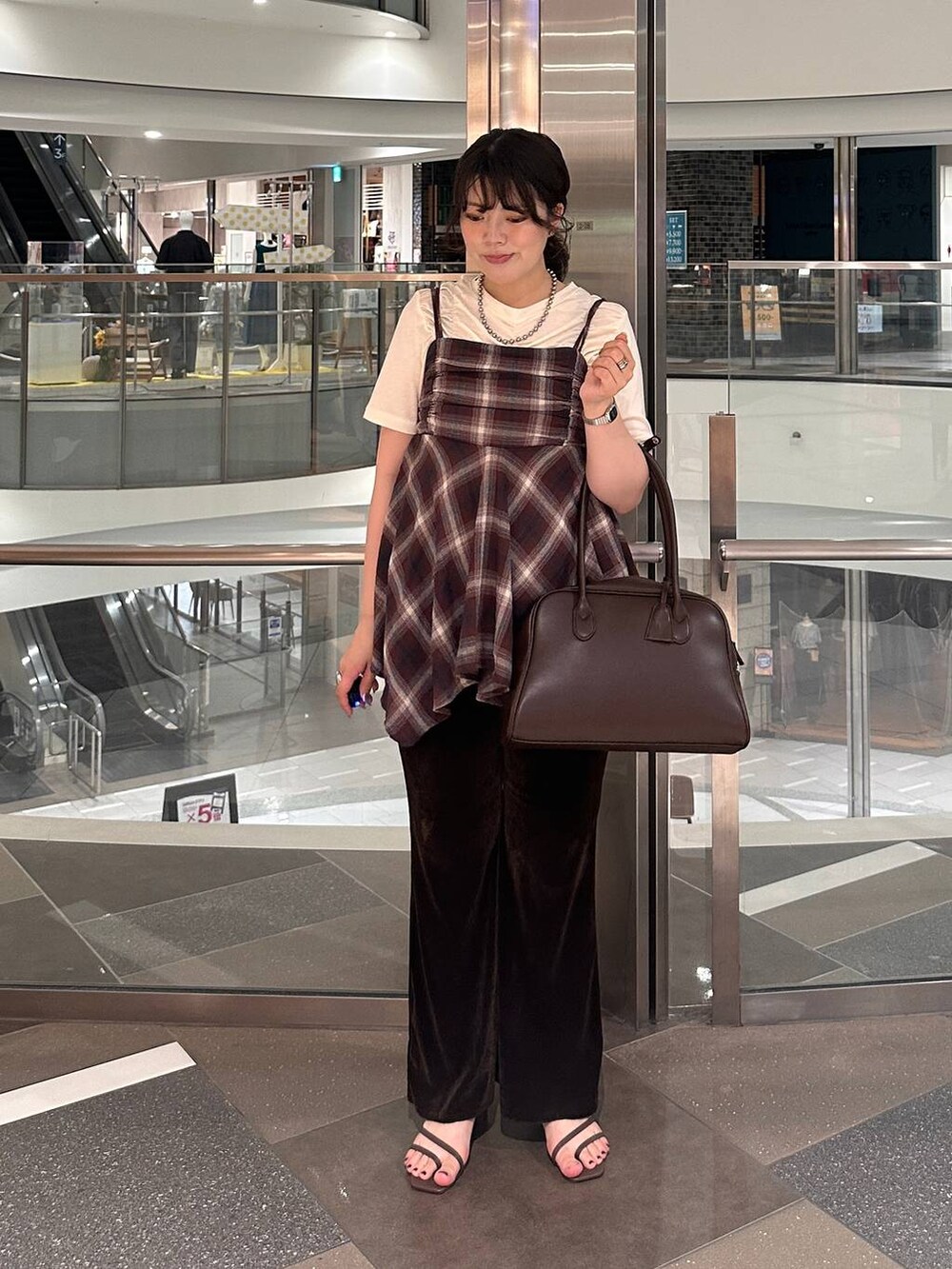 ブラウン系のサンダル、ブラウン系のボストンバッグ、レッド系のTシャツ/カットソーを着用したレディースの夏コーディネートの3枚目の写真