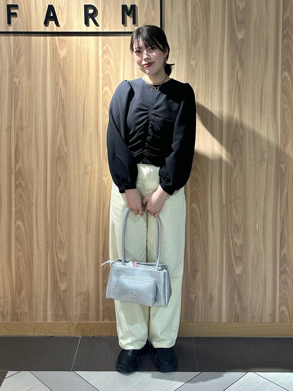 ブラック系のブーツ、シルバー系のショルダーバッグ、イエロー系のデニムパンツを着用したレディースの春コーディネートの3枚目の写真