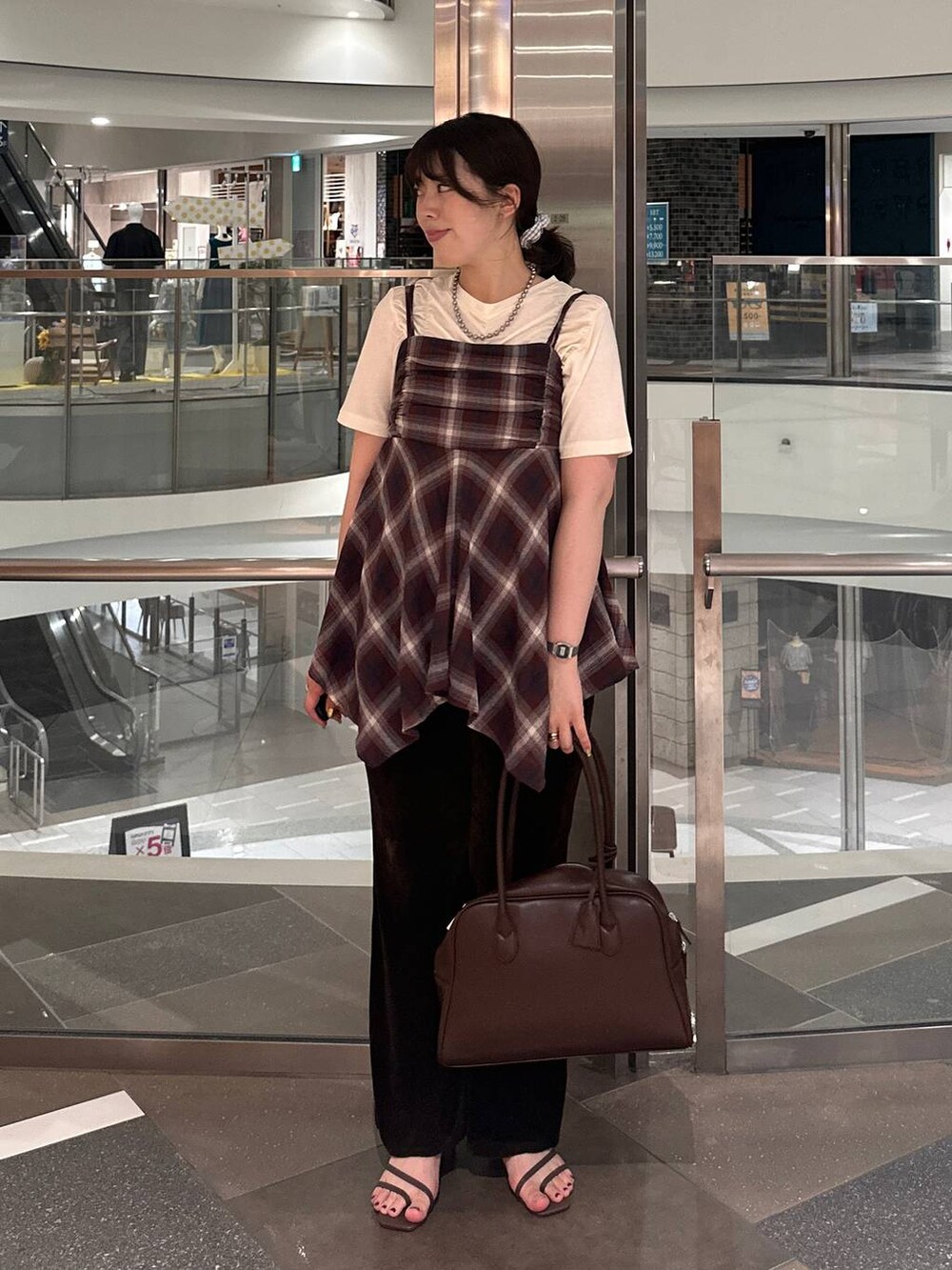 ブラウン系のサンダル、ブラウン系のボストンバッグ、レッド系のTシャツ/カットソーを着用したレディースの夏コーディネートの2枚目の写真