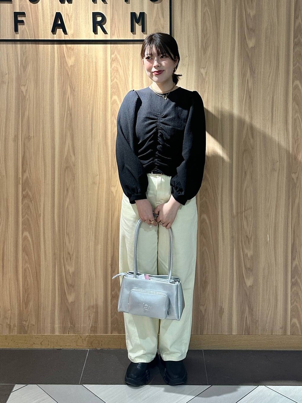 ブラック系のブーツ、シルバー系のショルダーバッグ、イエロー系のデニムパンツを着用したレディースの春コーディネートの2枚目の写真