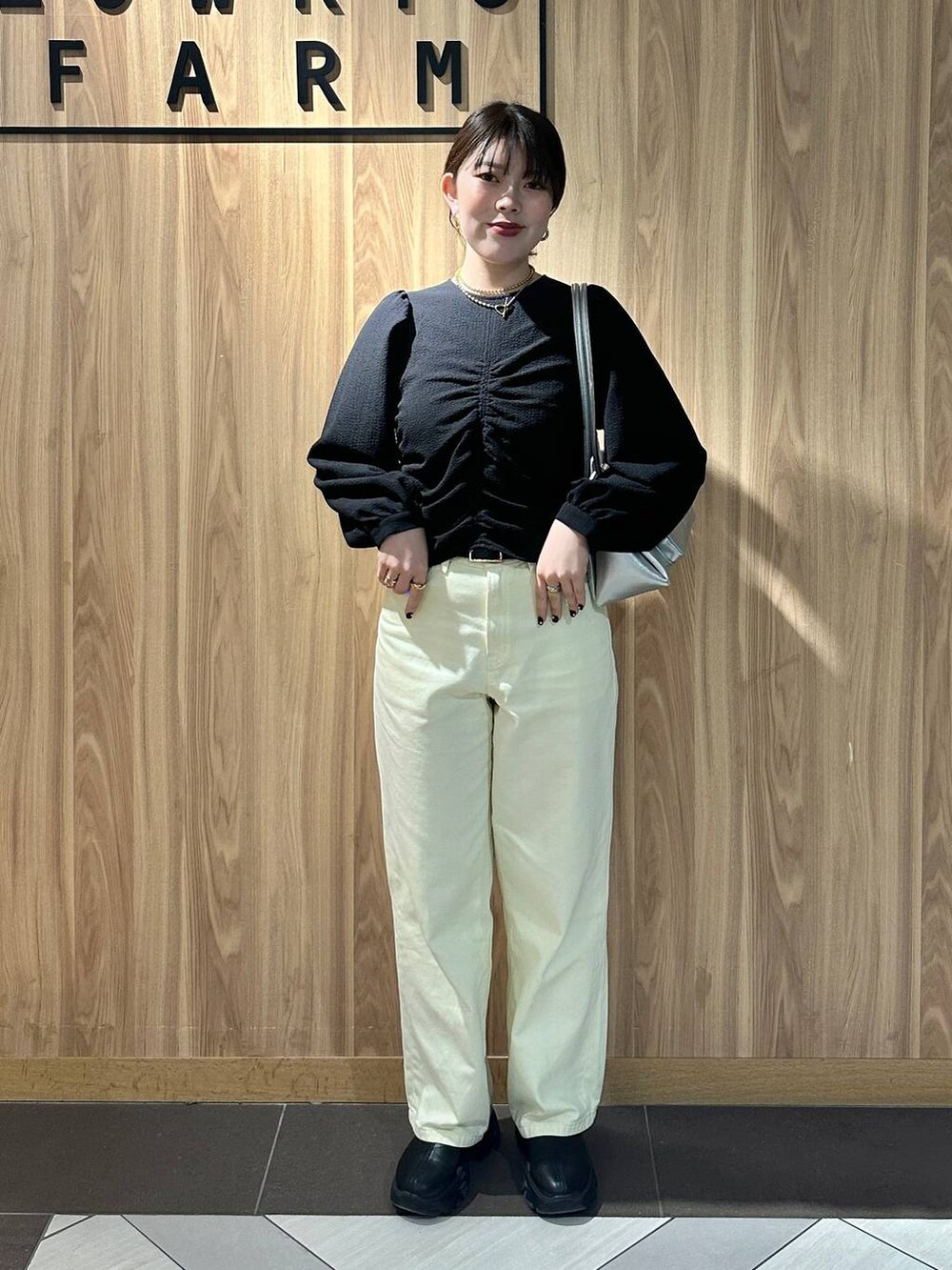 ブラック系のブーツ、シルバー系のショルダーバッグ、イエロー系のデニムパンツを着用したレディースの春コーディネートの4枚目の写真