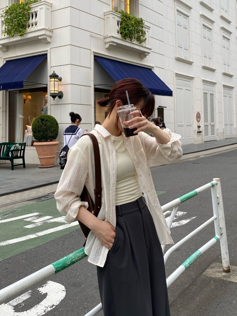 ブラック系のスラックス、ホワイト系のシャツ/ブラウス、ブラウン系のショルダーバッグを着用したレディースの夏コーディネートの2枚目の写真