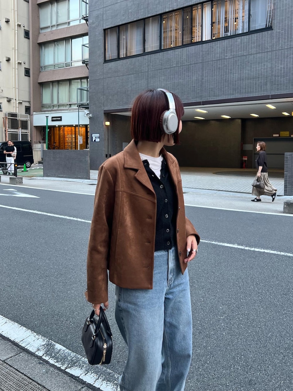 ブルー系のデニムパンツ、ブラック系のショルダーバッグ、ブラック系のカーディガン/ボレロを着用したレディースの秋コーディネートの3枚目の写真